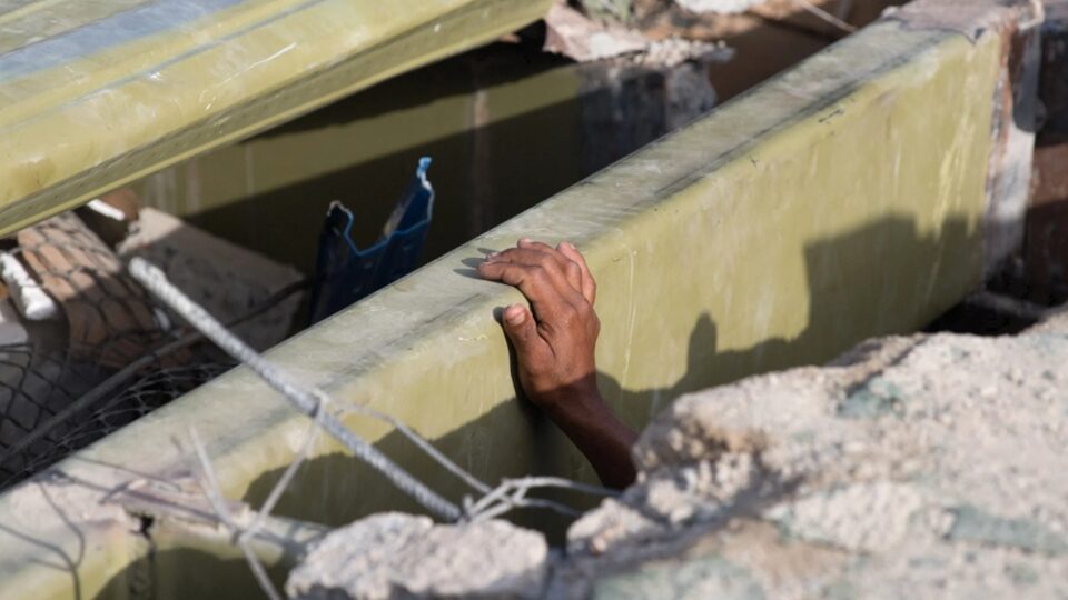 Una persona intenta salir de los escombros de un edificio tras los terremotos